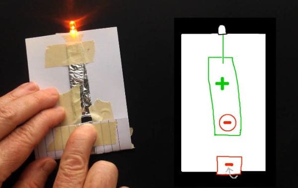 Student using a flashlight made from a few supplies and an index card