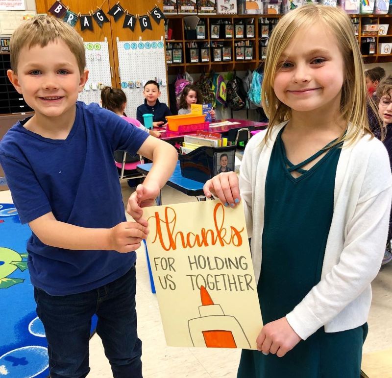 Two young students holding a sign that says "Thanks for holding us together"