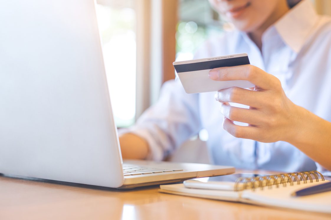 smiling woman holding a credit card working on a lap top computer