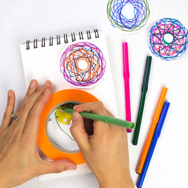 Hands working a DIY spirograph