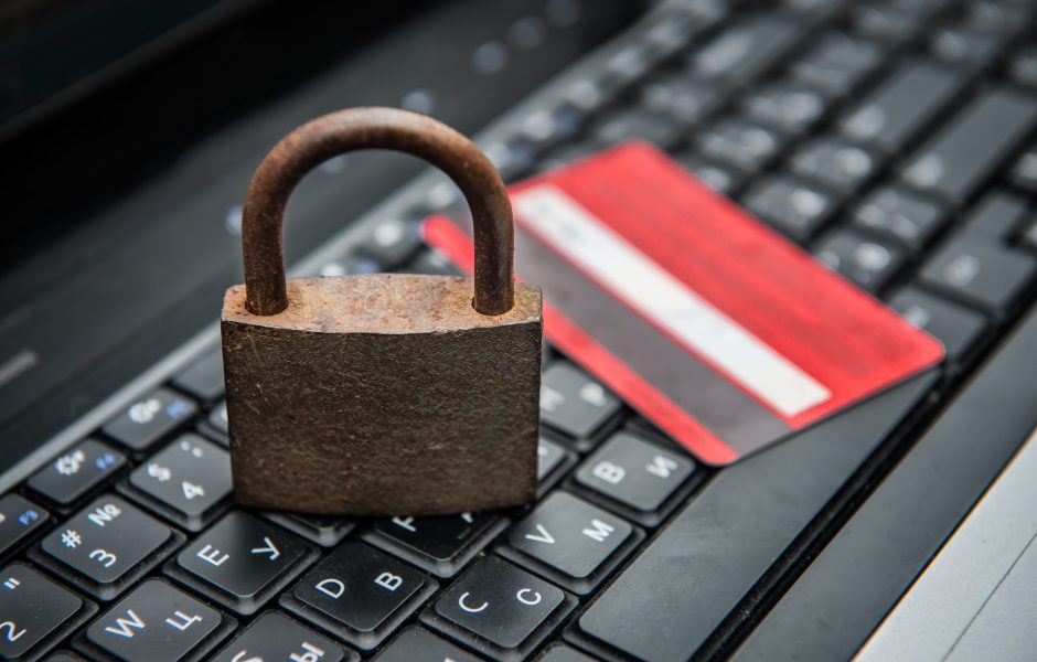 credit card and padlock sitting on a computer keyboard