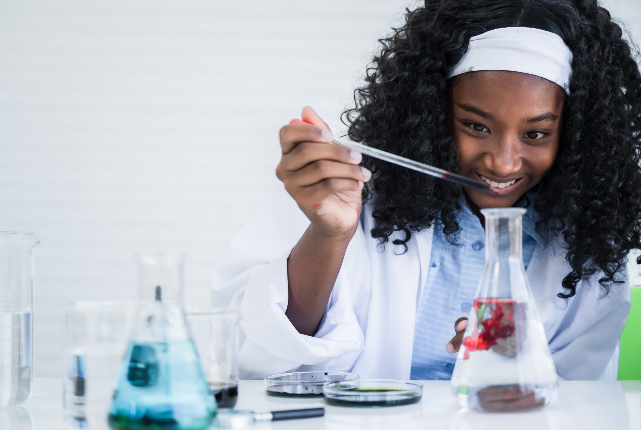 Girl student is learning and test science chemical with colorful liquid in beaker