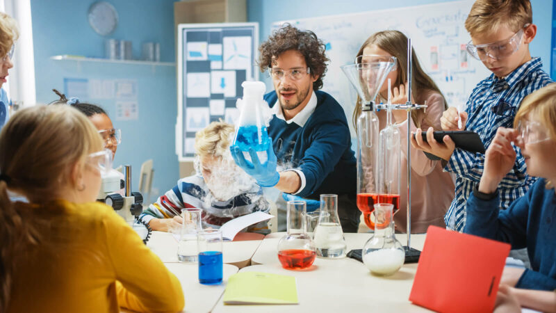 School Science Classroom: Enthusiastic Teacher Explains Chemistry to Diverse Group of Students. Science Resources for Middle and High School