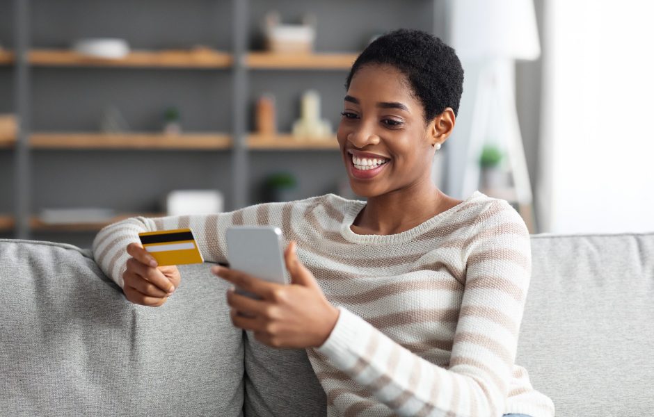 smiling woman using a credit card on a mobile phone