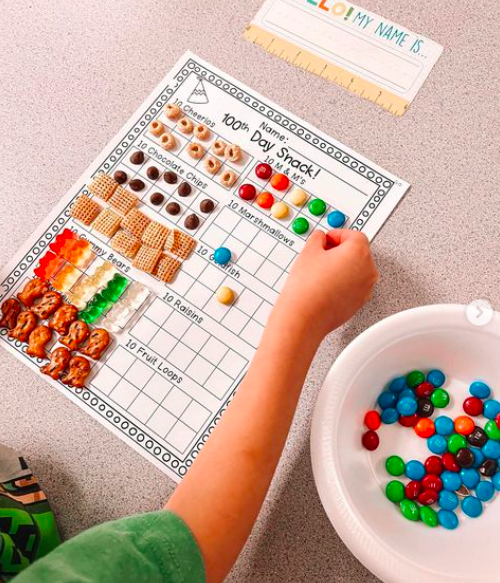 A student fill a hundreds chart with various snacks