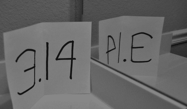 A sheet of paper with 3.14 is held up to a mirrow