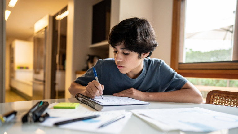 Photo of teenage student writing essay by hand, demonstrating digital detox many schools are considering