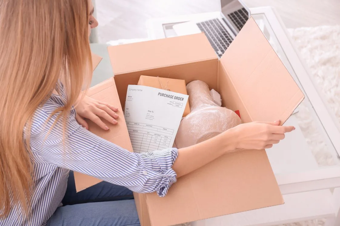 A young woman unpacks a lamp from an eCommerce delivery.